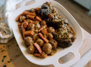 Slow cooker pot roast served on a platter with tender beef, carrots, and baby potatoes in rich gravy.