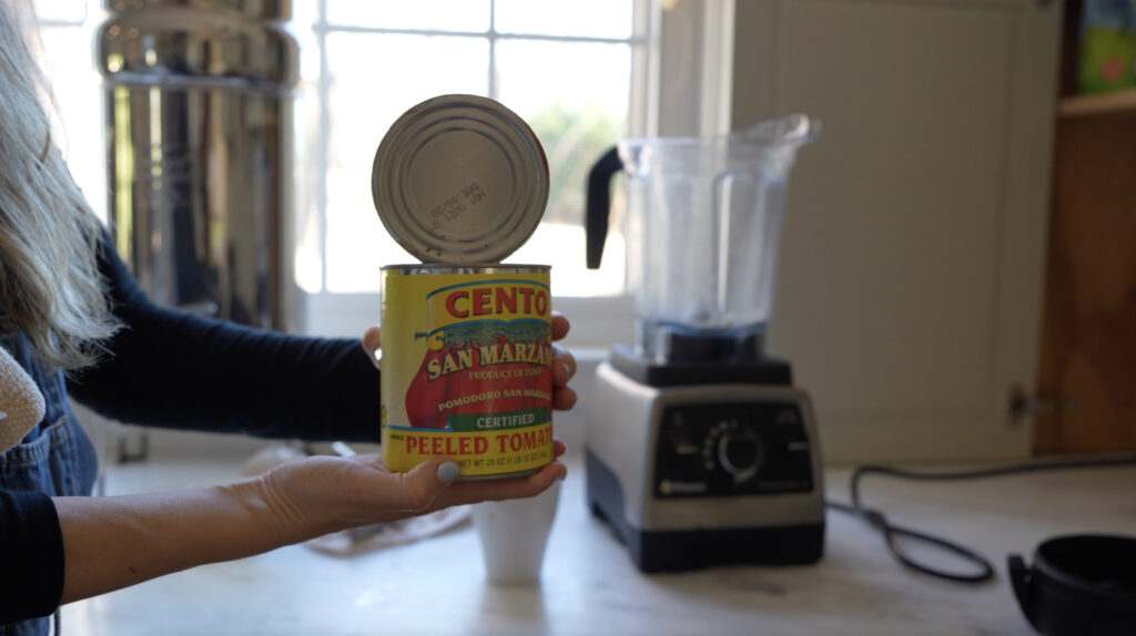 A can of San Marzano tomato going into a blender for marinara sauce