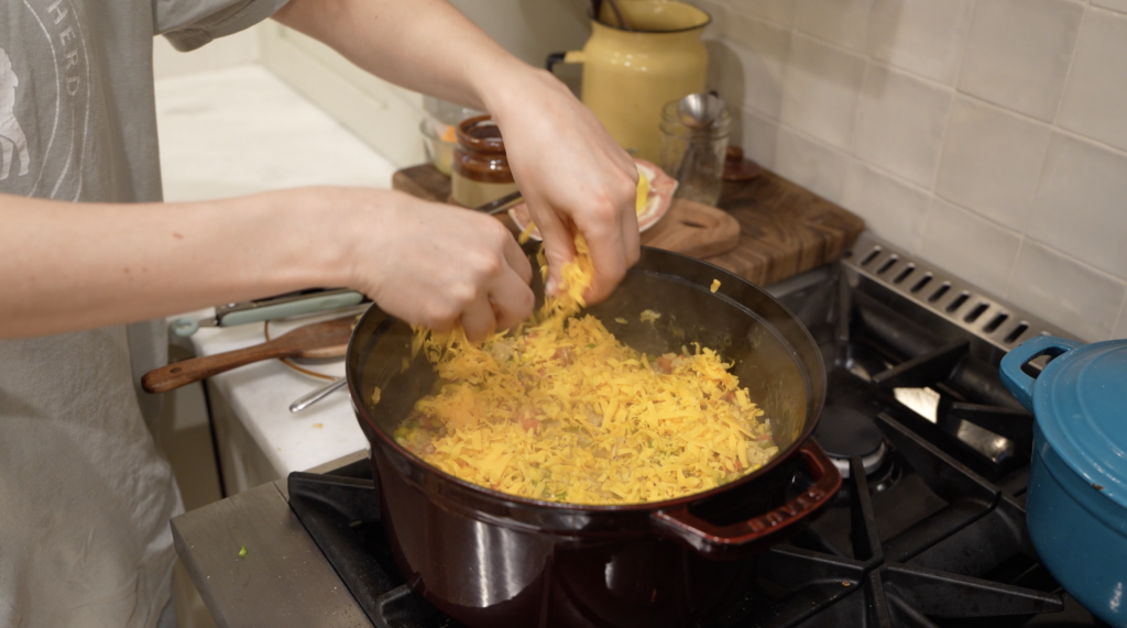 woman topping rice skillet meal with cheese