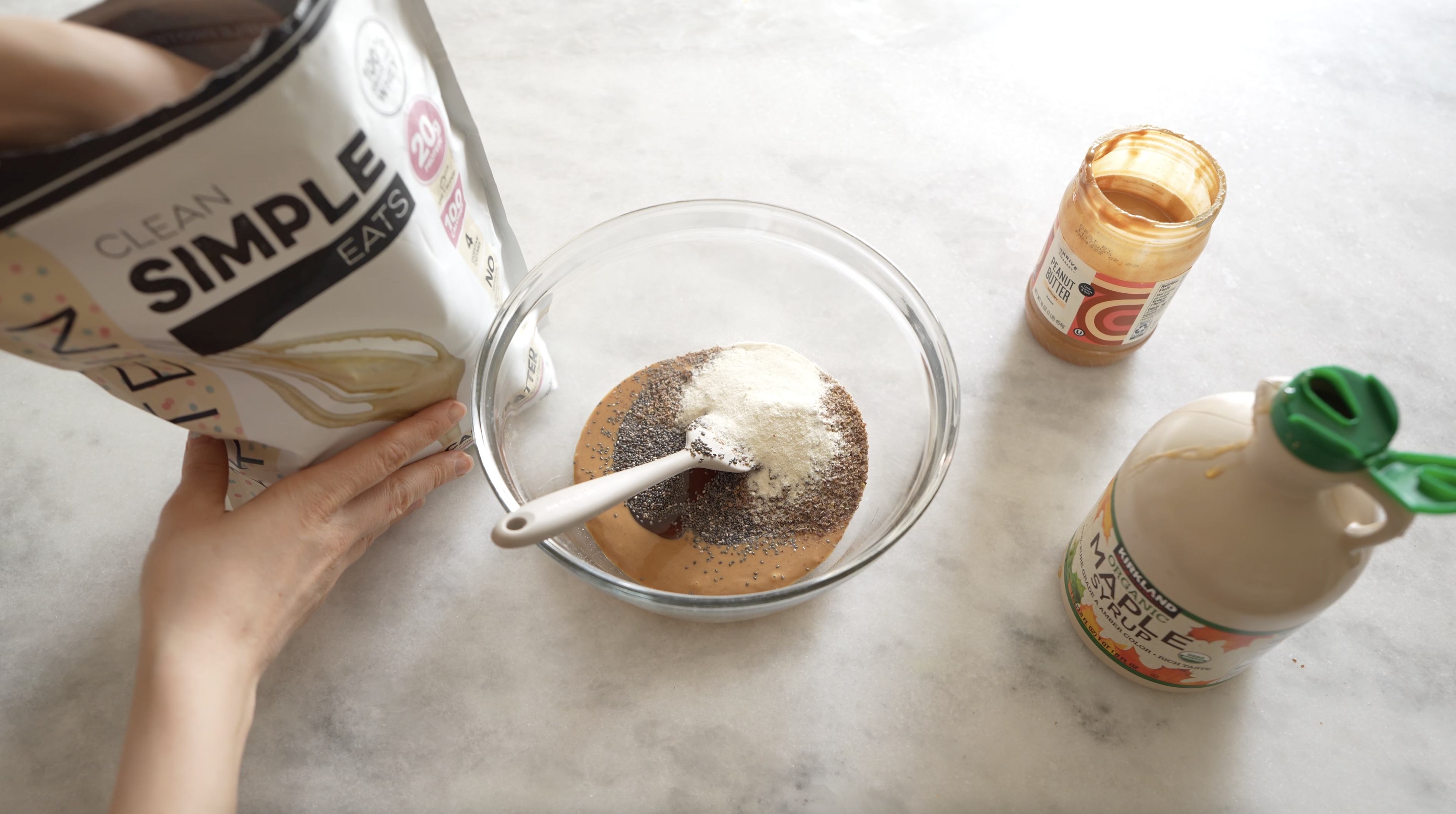 peanut butter energy bites in a bowl with clean simple eats protein powder on a counter