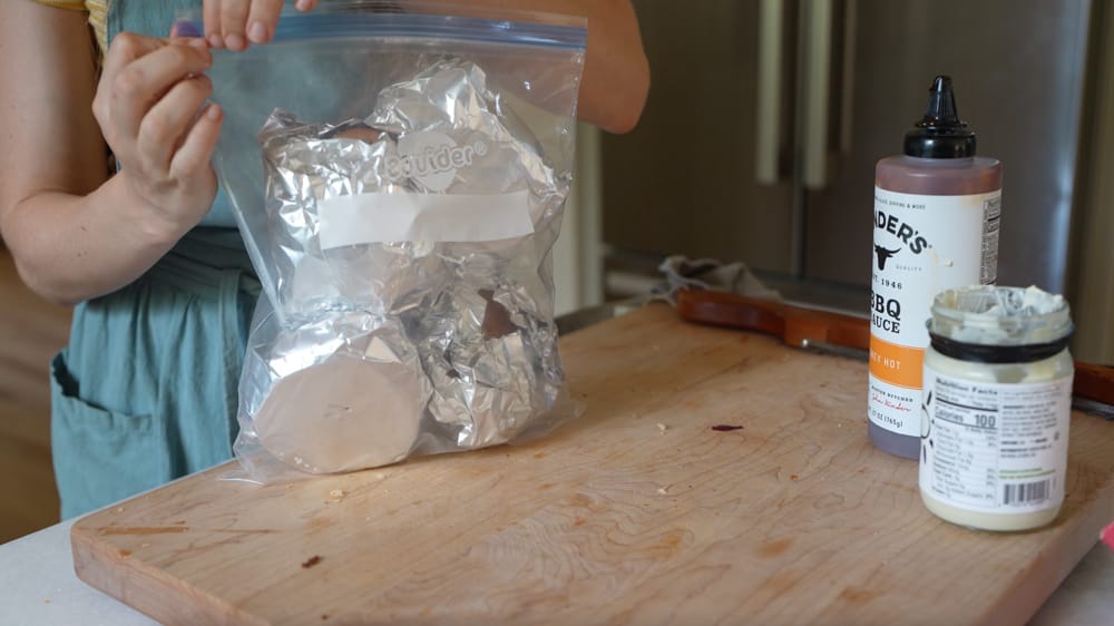 woman packing bbq chicken sandwiches to go