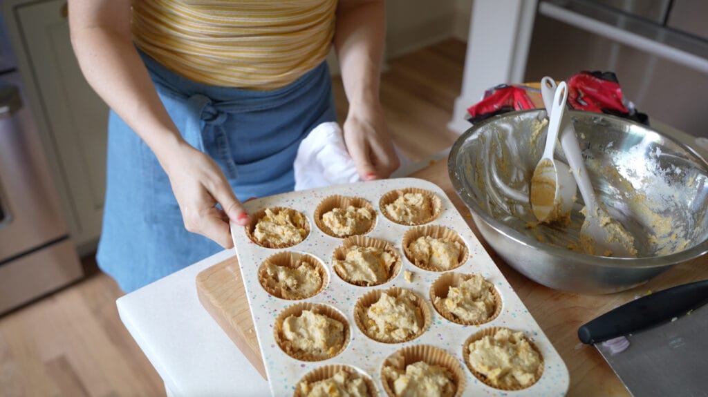 filling the muffin tin with cheesy cornbread muffin batter