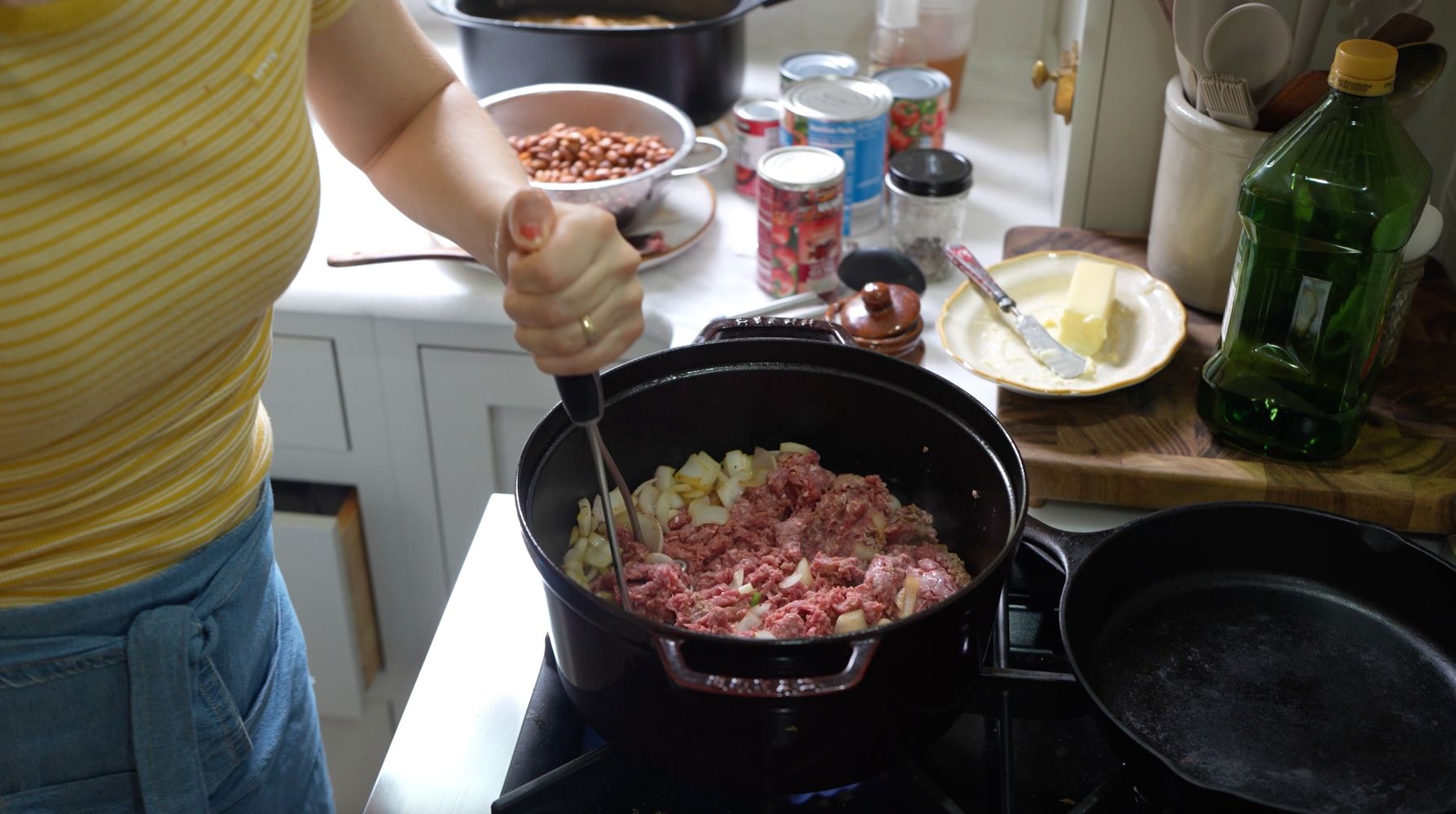 Ground beef browning in a large pot with sautéed onions for chili