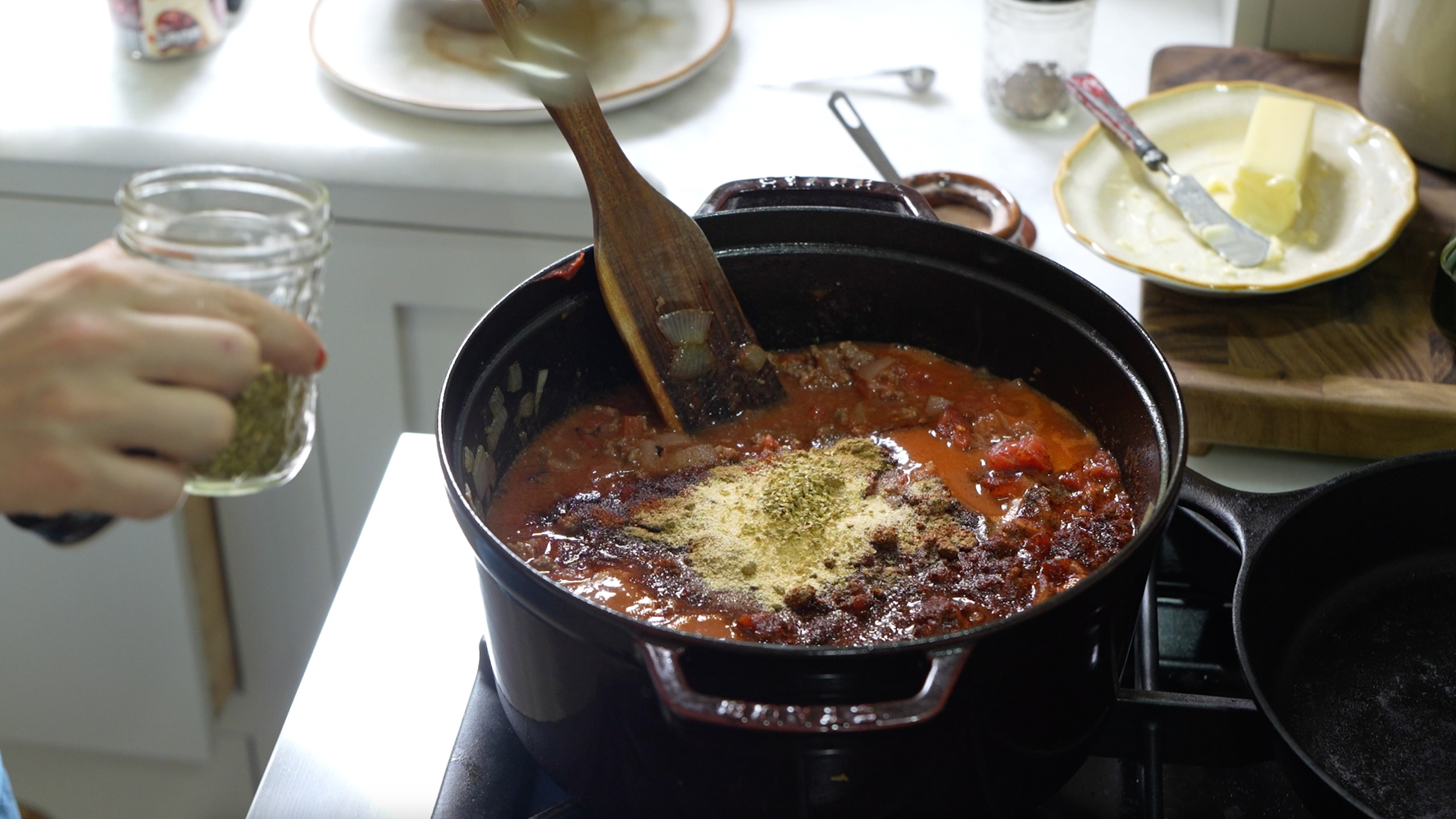adding spices to simmering chili