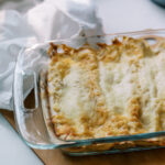 Freshly baked salsa verde chicken enchiladas topped with melted golden cheese in a glass dish.