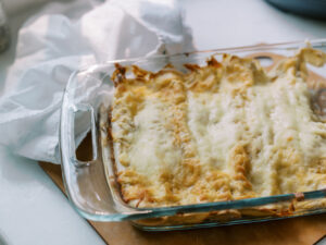 Freshly baked salsa verde chicken enchiladas topped with melted golden cheese in a glass dish.