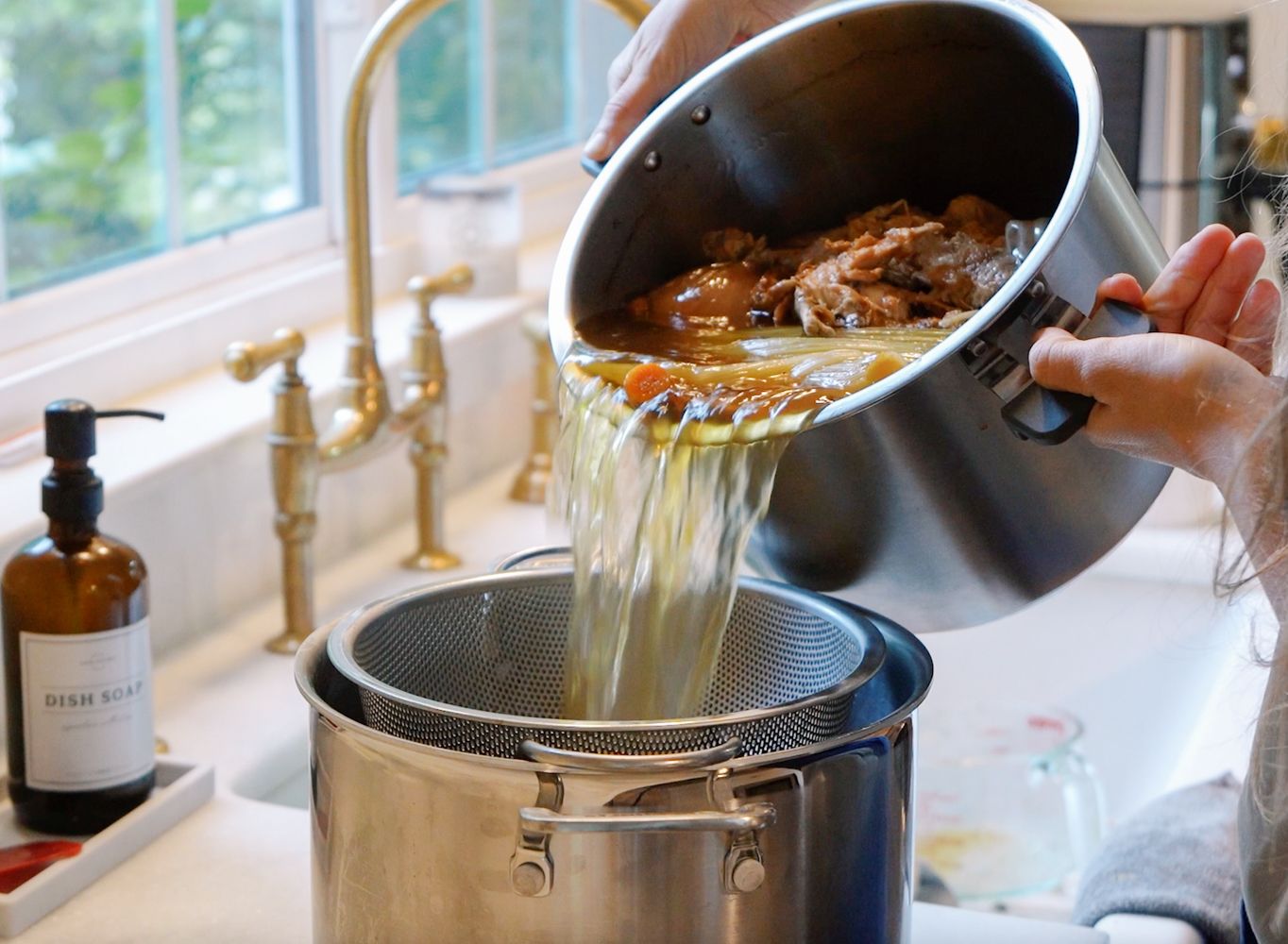 Roasted chicken bones, onions, celery, and garlic being added to an Instant Pot for homemade bone broth.