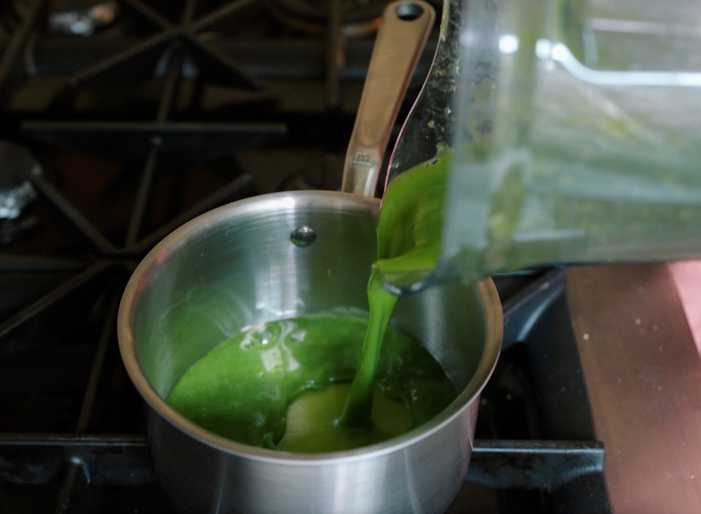 pouring green gummy snack mixture into saucepan