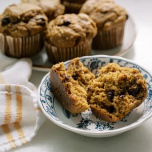 Fresh-milled pumpkin banana muffins with chocolate chips, sliced open to show a moist, fluffy texture on a blue floral plate.