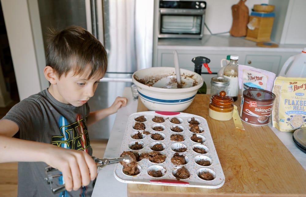 little boy scooping chocolate banana mini muffins