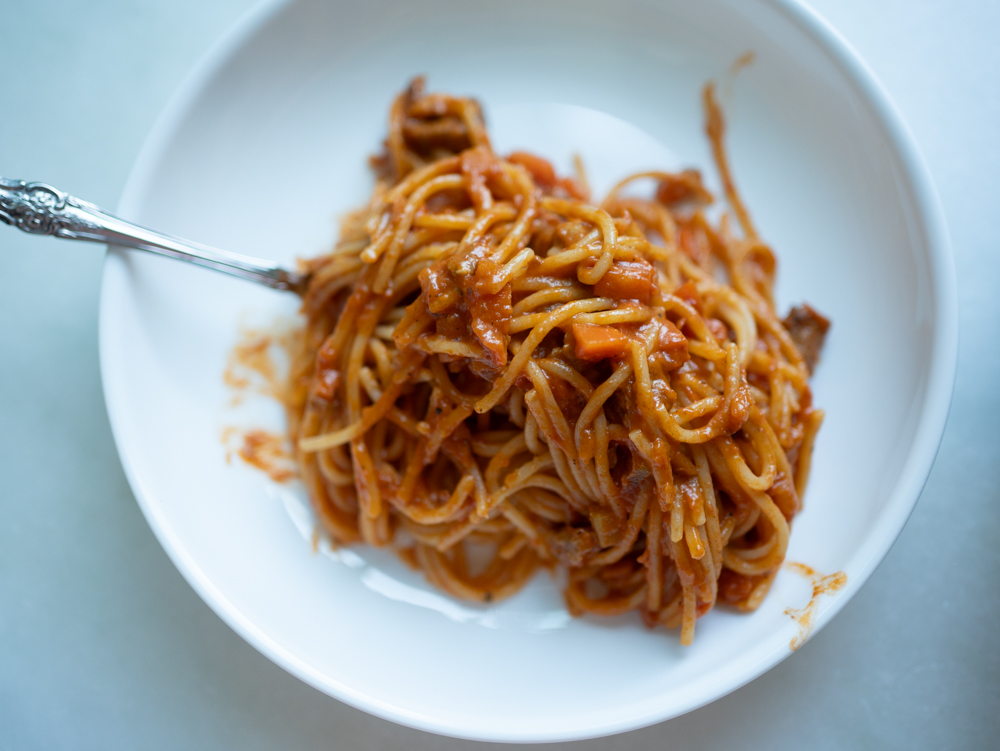a delicious bowl of spaghetti with sausage and carrots